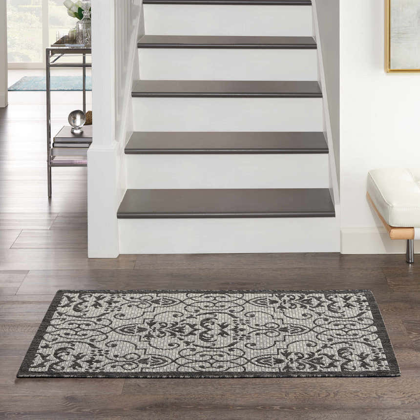 Entryway with Nourison Country Side Ivory/Charcoal rug on dark wood floors, stairs, and white bench.