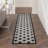 Hallway with Nourison Aloha Black White Modern Area Rug runner on wood floor, console table, neutral walls.