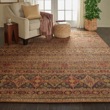 Living room scene with Nourison Jewel Blue Red Moroccan rug, beige armchair, and woven ottoman.