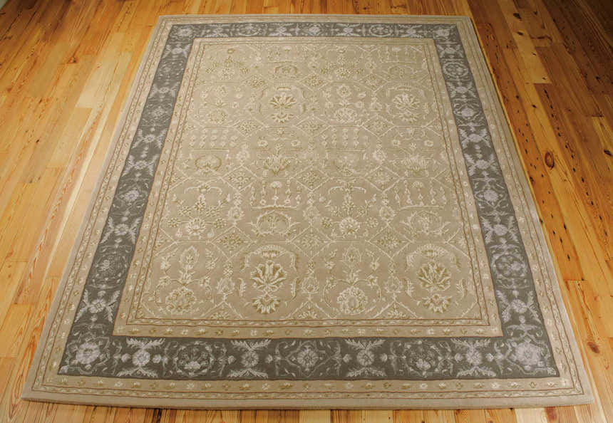 Close-up of the sand-colored Nourison Regal Persian rug. Features a floral pattern and gray border on a wood floor.