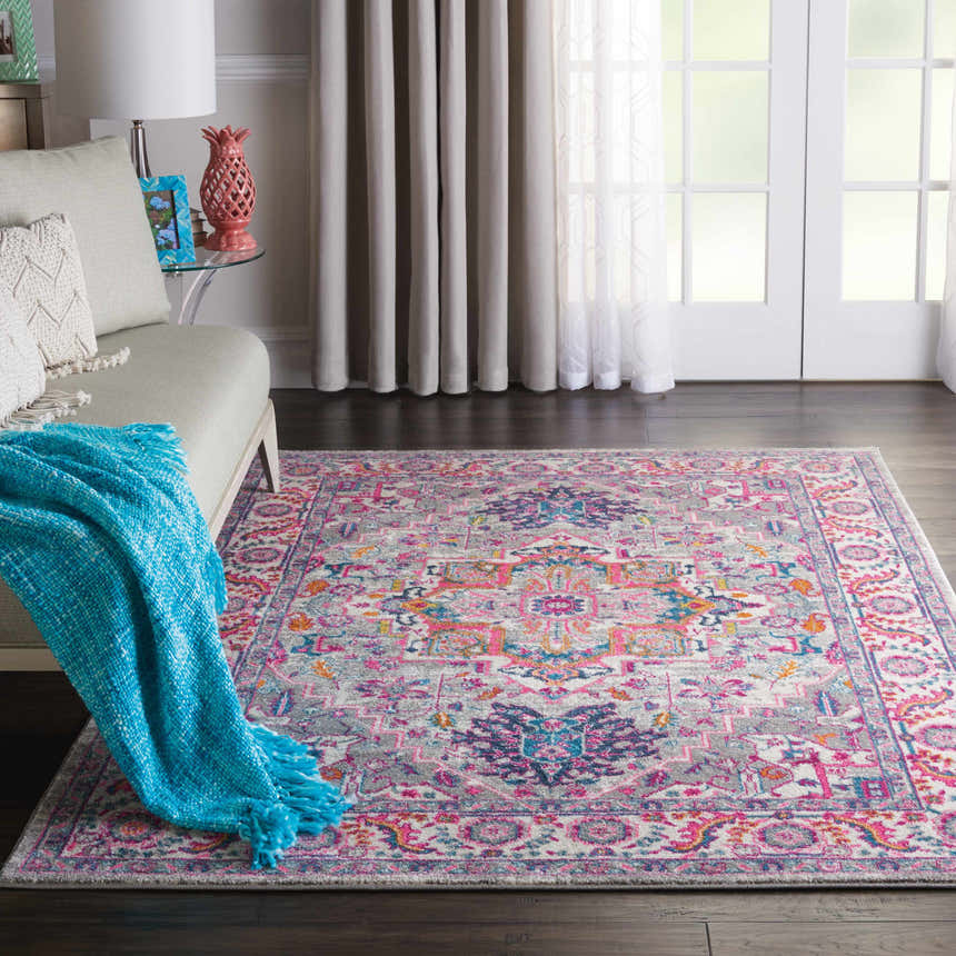Living room scene with a Nourison Passion Light Grey Pink Bohemian Indoor Area Rug, sofa, and bright accents.