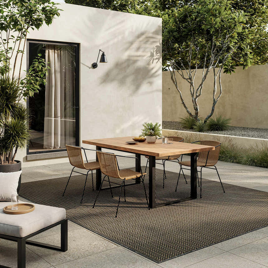 Modern patio with wood table and Nourison Horizon Charcoal rug. Outdoor living space.