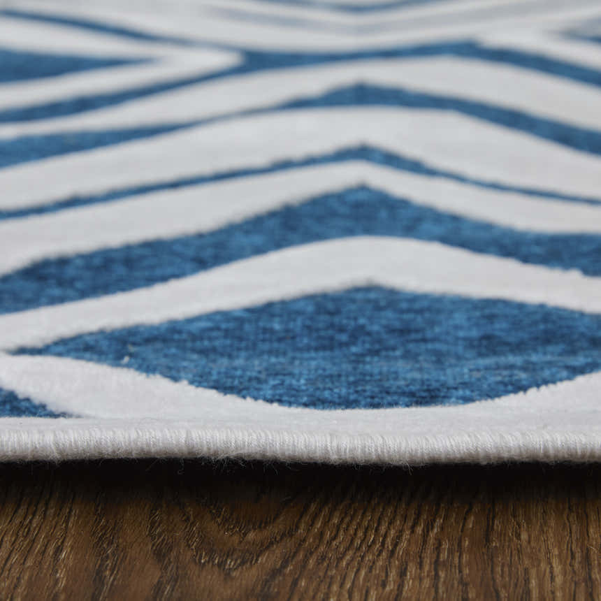 Close up of Feizy Saphir Mira rug showing blue and white diamond pattern and soft texture on wood floor. Pile