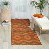 Bright room featuring Nourison Spectrum Flame Chocolate runner rug, white bench, and potted plants.