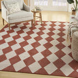 Living room scene with a Nourison Positano Terracotta rug, striped armchair, wood side table, and neutral sofa.