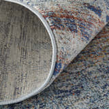 Close-up of Feizy Edgemont rug showing blue, ivory, and orange abstract design and jute, polyester, polypropylene texture. Fold