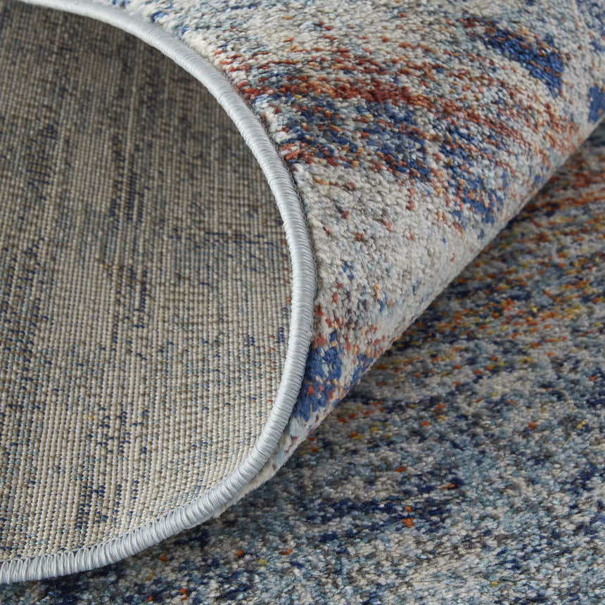 Close-up of Feizy Edgemont rug showing blue, ivory, and orange abstract design and jute, polyester, polypropylene texture. Fold