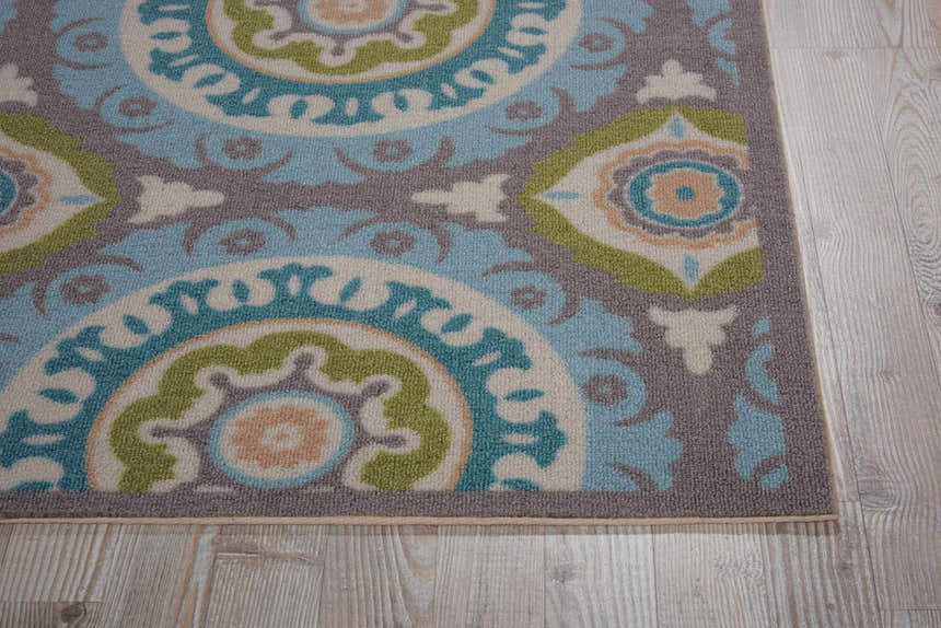 Close-up of Waverly Sun N' Shade Jade rug. Coastal style rug with jade, blue, gray, and cream circular floral pattern.