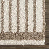 Close-up of the Jola Beige Area Rug, showcasing its textured shag pile and geometric striped pattern in beige, camel, and white. Swatch