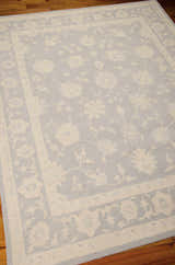 Close-up of the Nourison Zephyr Light Blue rug, showcasing its floral pattern and border on a wood floor.