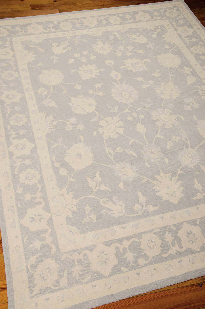 Close-up of the Nourison Zephyr Light Blue rug, showcasing its floral pattern and border on a wood floor.