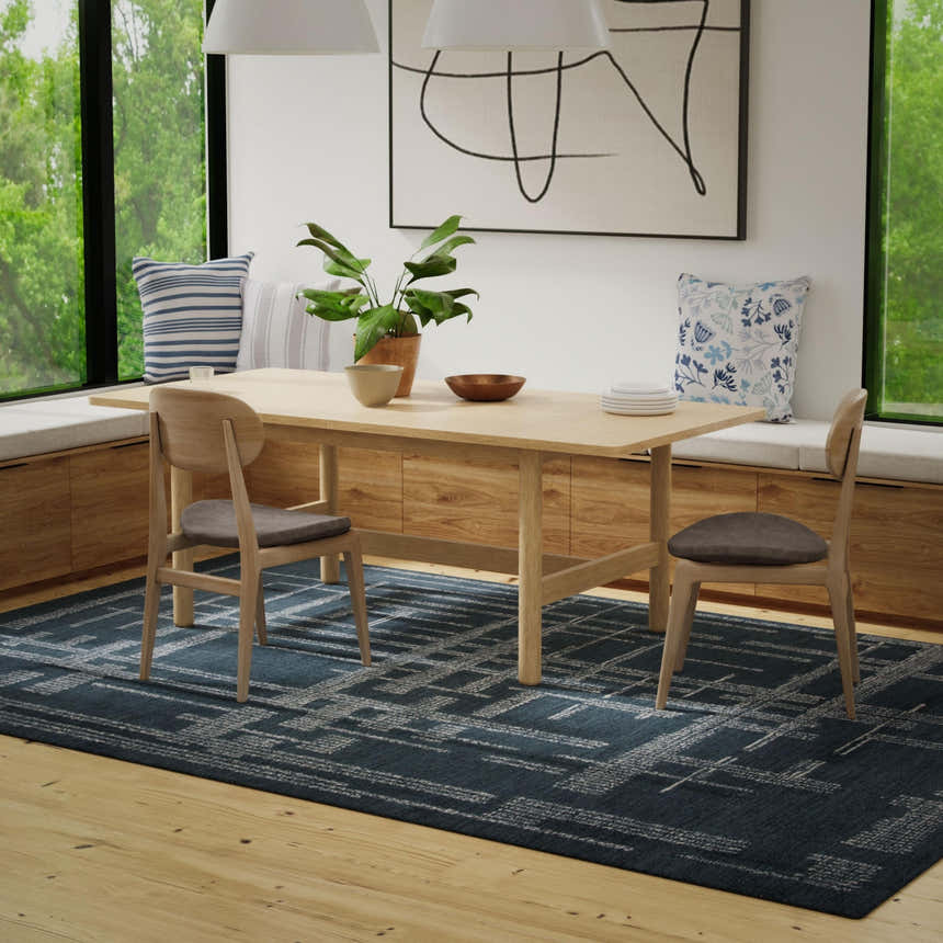 Dining room with a blue and ivory Rizzy BX05BL area rug, wood table, and built-in bench seating by a large window. Roomscene-Rectangle