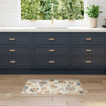 Farmhouse kitchen scene with Nourison Aloha Grey Multicolor rug, blue cabinets, wood floors, and garden view.