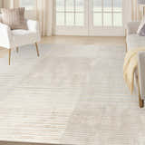 Living room scene with a Nourison Splash Beige Silver rug, white chairs, light wood floors, and natural light.