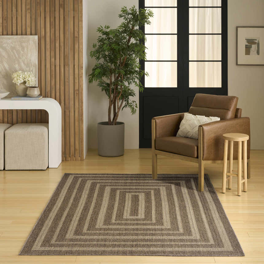 Living room scene with a brown leather chair and the Nourison Tulum Brown Outdoor Area Rug.