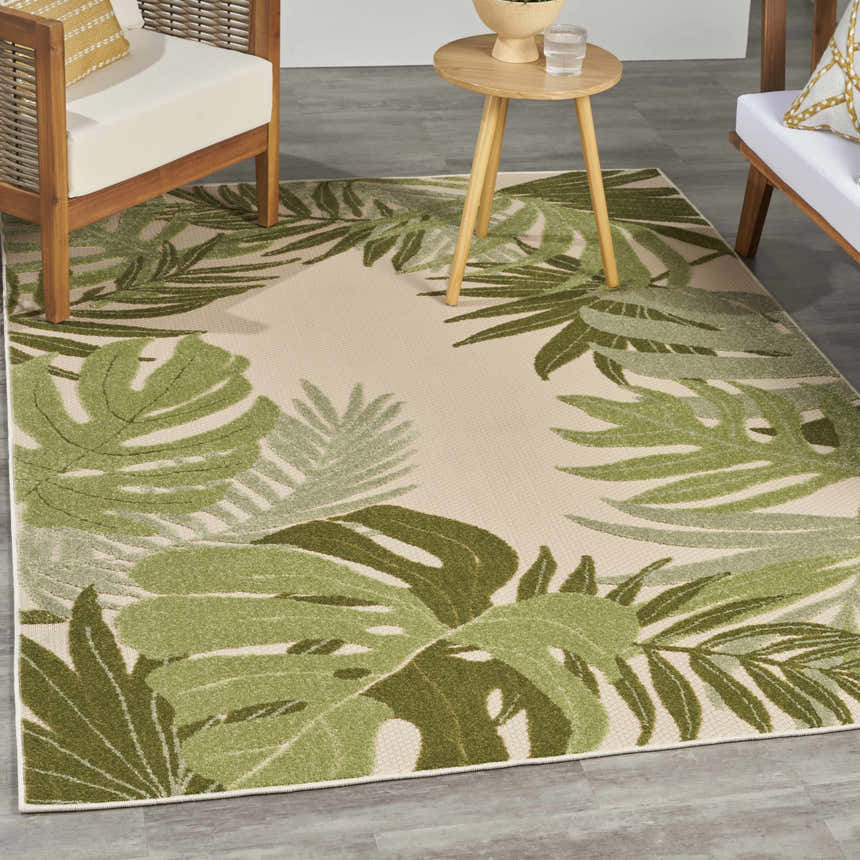 Outdoor patio scene with a Nourison Aloha Ivory Green Area Rug featuring a tropical leaf pattern.