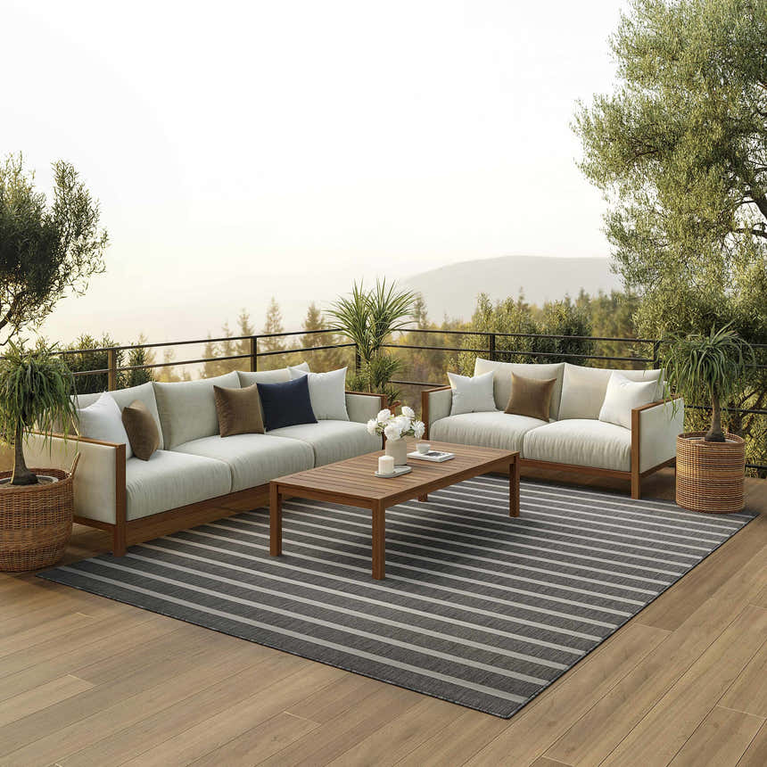 Outdoor patio with sofas, wood table, and Nourison Positano Charcoal Ivory rug with gray and ivory stripes.