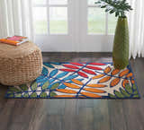 Entryway with Nourison Aloha Multicolor Tropical Area Rug, jute pouf, green vase, and dark wood floors.