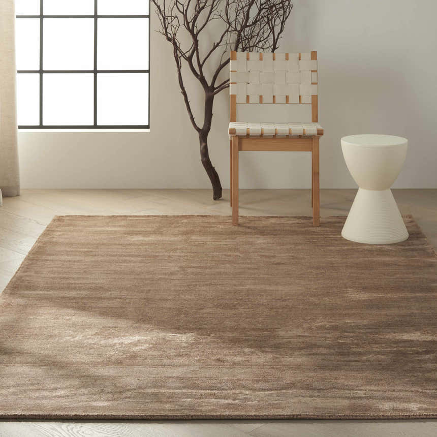 Minimalist room with a Calvin Klein Home Lunar Foal area rug, woven chair, and white accent table.