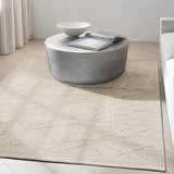 Minimalist living room with taupe Calvin Klein CK044 Wander rug, round coffee table, and neutral sofa.