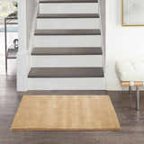 Entryway with Plush Cloud Camel rug, dark wood floors, white stairs, and modern bench.