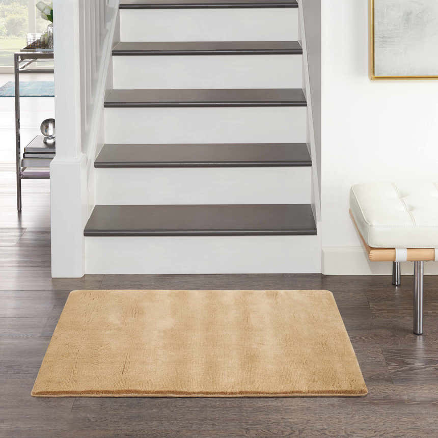 Entryway with Plush Cloud Camel rug, dark wood floors, white stairs, and modern bench.