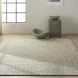 Minimalist room with a Calvin Klein Home Lowland Basalt rug, concrete accents, and natural light.