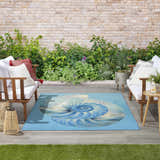 Coastal patio with white sofas and Nourison Color Splash Blue Ivory Area Rug featuring a nautilus shell design.