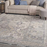 Living room scene with a beige sofa, blue pillows, and a Nourison Lynx Ivory Charcoal Vintage Area Rug.