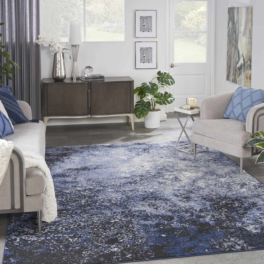 Living room scene with a Nourison Passion Light Blue Black rug, grey sofa and armchair, and modern decor.