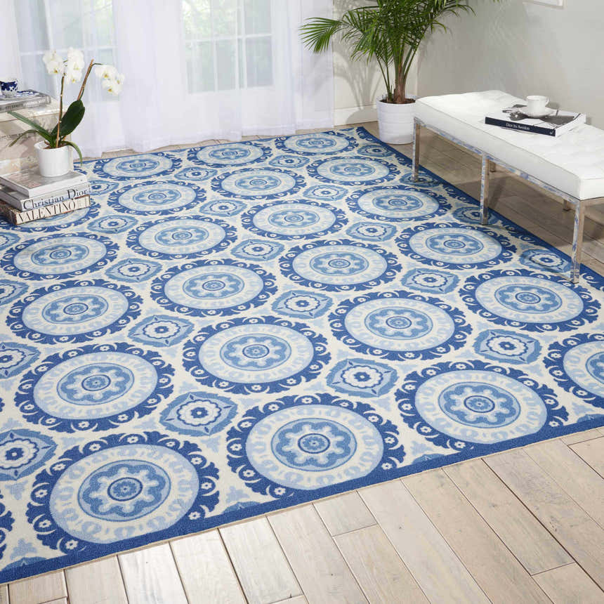 Bright living room with Waverly Sun N' Shade Navy Coastal Area Rug, white bench, wood floors, and natural light.