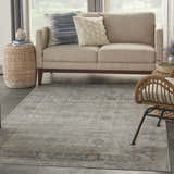 Living room scene with a Nourison Malta Cloud vintage rug, beige sofa, and woven accents.