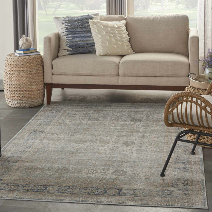 Living room scene with a Nourison Malta Cloud vintage rug, beige sofa, and woven accents.