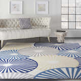 Living room scene with a Nourison Grafix White rug featuring blue, gray, and beige circle patterns under a white tufted sofa.