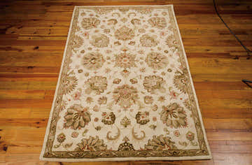 Close-up of Nourison Jaipur Ivory Persian rug showing chestnut floral pattern and handmade wool texture on wood floor.