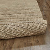 Close-up of the hand woven Feizy Kaelani rug in tan, ivory, and taupe on a wood floor, showing the jute texture. Fold