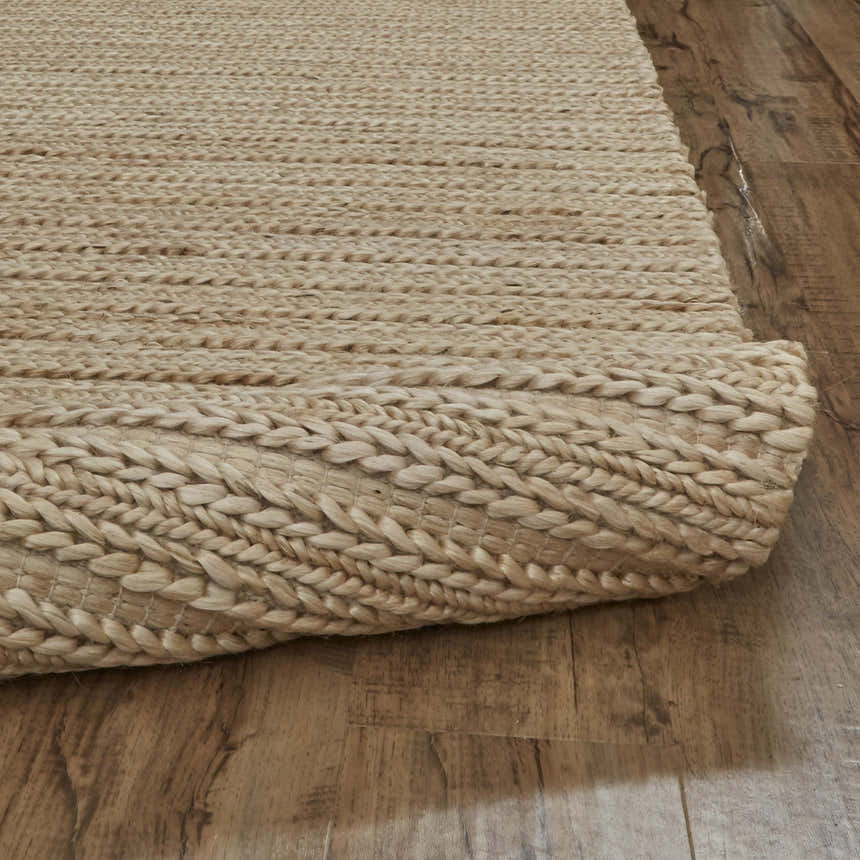 Close-up of the hand woven Feizy Kaelani rug in tan, ivory, and taupe on a wood floor, showing the jute texture. Fold