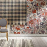 Close up of the Chilliwack Gray Plaid Wool Rug showing charcoal, cream, and tan colors with a gray chair. Styleshot