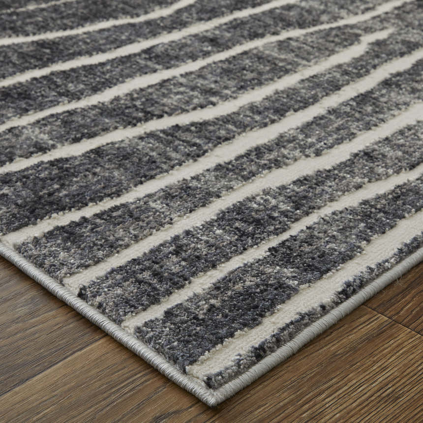 Close-up of Feizy Kano rug featuring black, gray, and ivory stripes on a textured surface. Transitional abstract design. Corner
