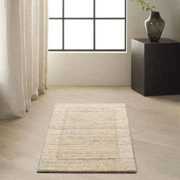 Minimalist room scene with a Calvin Klein CK082 Ridge beige ivory farmhouse rug on light wood floors. Neutral drapes and black accents.