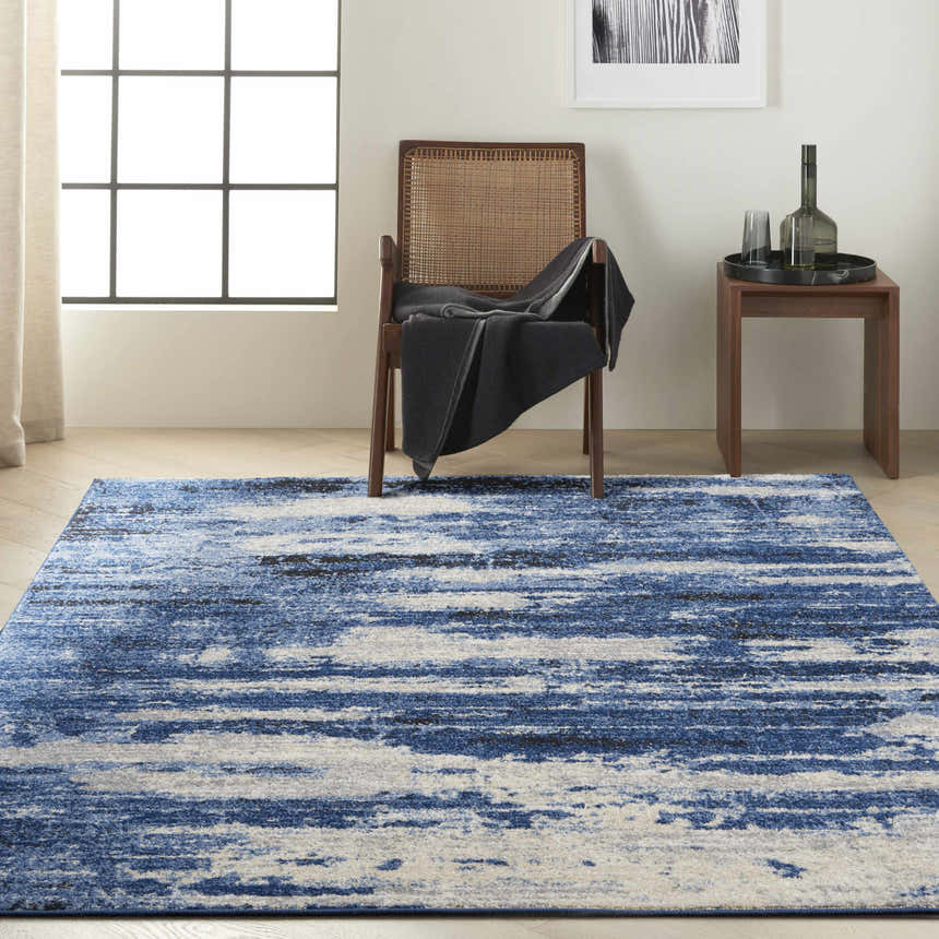 Modern room scene with blue grey Calvin Klein River Flow rug, wood chair, and side table.