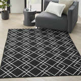 Modern living room with gray chair and Nourison Modern Lines Black rug featuring a white geometric pattern.