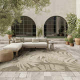 Outdoor patio scene with a Nourison Aloha Ivory Sage rug, sectional sofa, and potted plants.