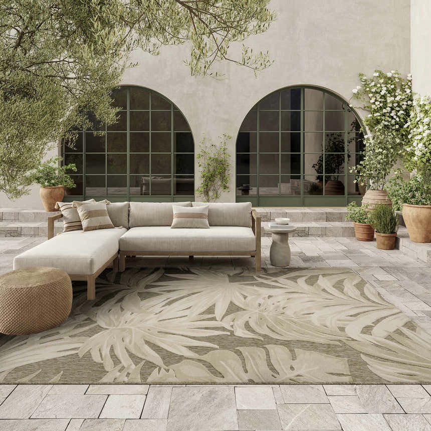 Outdoor patio scene with a Nourison Aloha Ivory Sage rug, sectional sofa, and potted plants.