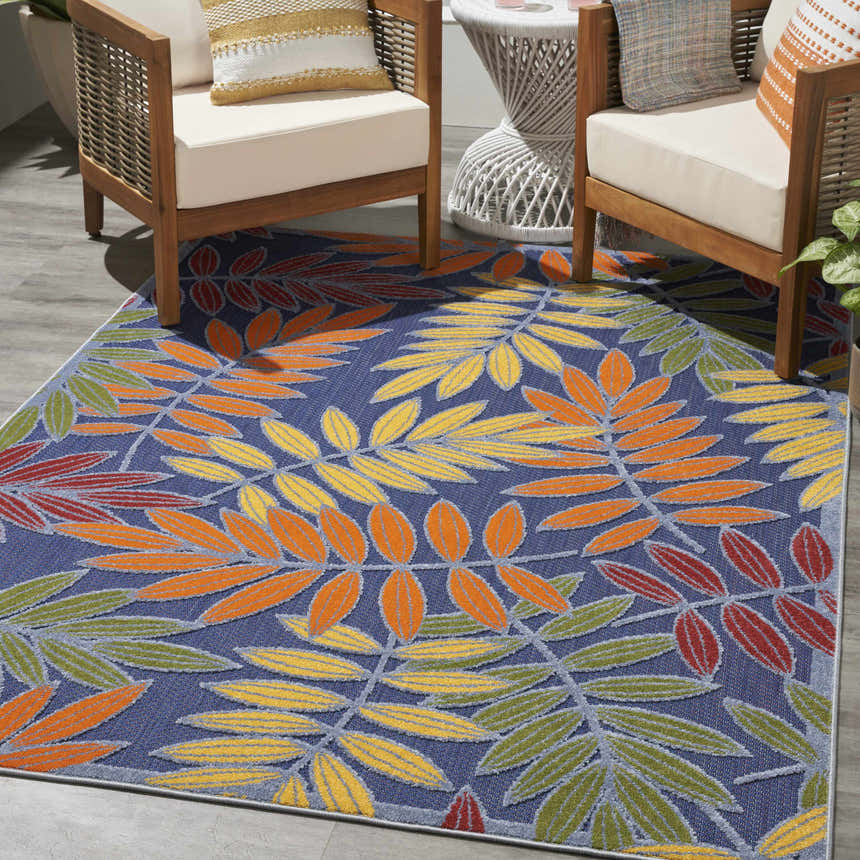 Outdoor patio scene with Nourison Aloha Navy Multicolor rug, wood chairs, and woven table.