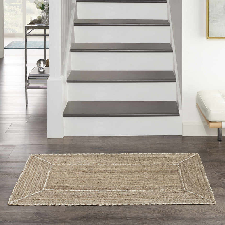 Farmhouse foyer with Nourison Terrazzo Jute Natural Grey rug on wood floor. Staircase and modern console table.