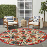 Outdoor patio scene with a round Nourison Aloha Red Multicolor Farmhouse Area Rug, chairs, and green accents.