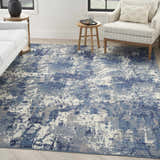 Living room scene with a Nourison Grafix Navy Blue rug, white sofa, and light wood accents. Modern, airy feel.