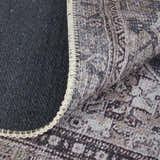 Close-up of the Feizy Percy rug showing gray, ivory, and taupe medallion pattern, edge binding, and rug backing. Fold