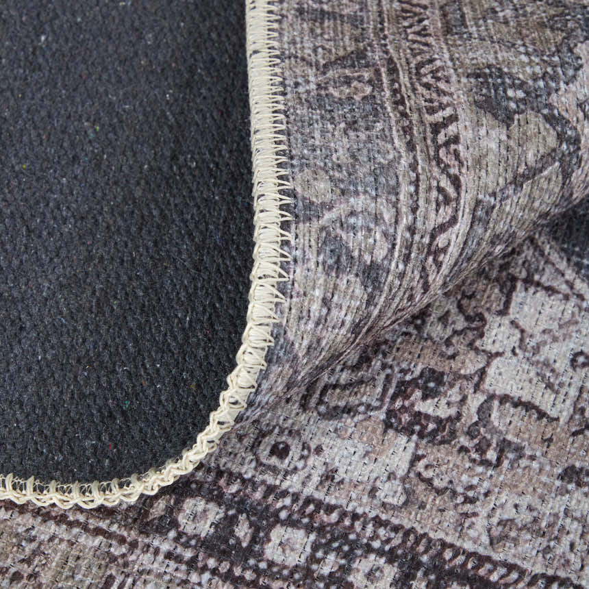 Close-up of the Feizy Percy rug showing gray, ivory, and taupe medallion pattern, edge binding, and rug backing. Fold